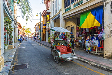 A local rickshaw (tuk tuk) driver in a colourful street scene in George Town, Penang Island, Malaysia, Southeast Asia, Asia