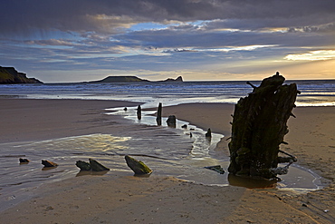 Sunset over the wreck of the Helvetia and Worms Head at Rhossili Bay, Gower, Wales, United Kingdom, Europe