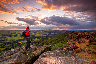 A male walker standing on Curbar Edge at sunset, Peak District, Derbyshire, England, United Kingdom, Europe