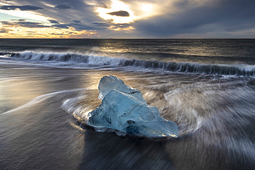 Glacier ice on black sand with crashing waves, near Jokulsarlon, South Iceland, Iceland, Polar Regions