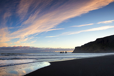 Looking towards the sea stacks of Reynisdrangar at sunset from the black volcanic sand beach at Vik i Myrdal, South Iceland, Iceland, Polar Regions