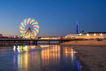 Big wheel and amusements on Central Pier at sunset with Blackpool Tower, Blackpool, Lancashire, England, United Kingdom, Europe