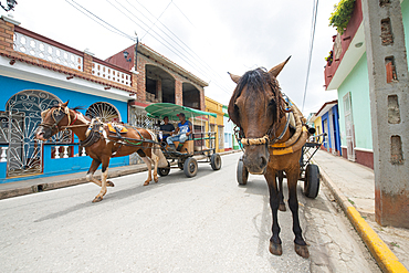 Horses pulling carts along a street in Trinidad, Cuba, West Indies, Caribbean, Central America