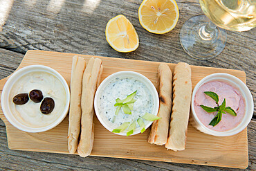 Meze at a Cypriot restaurant of Taramasalata, tzatziki, hummus, pitta bread, lemon and olives accompanied with white wine, Cyprus, Mediterranean, Europe