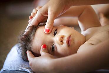 Baby massage lesson with a certified masseur, a young mother learns how to massage her 1-year old son.