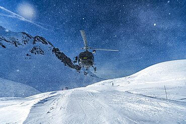 Mountain rescue team helicopter rescuing an injured skier after having a skiing accident in the Alps mountains, at Avoriaz, France, Europe