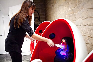 Reportage in a smile bar in Paris, France. Teeth whitening involves applying a whitening paste using a special mouthpiece, then exposing the teeth to a LED lamp which sets off the whitening process.