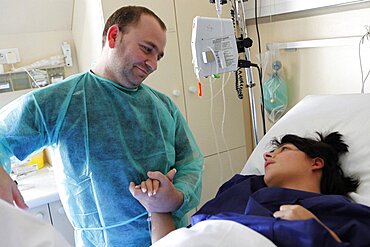 Woman in labor holding husband's hand in hospital