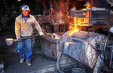 Takahiro Koizumi carries molten iron with spoon to pour it into the mold, to make a iron teapot or tetsubin, nanbu tekki, Workshop of Koizumi family,craftsmen since 1659, Morioka, Iwate Prefecture, Japan