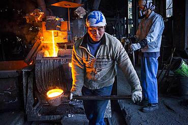 Takahiro Koizumi carries molten iron with spoon to pour it into the mold, to make a iron teapot or tetsubin, nanbu tekki, Workshop of Koizumi family,craftsmen since 1659, Morioka, Iwate Prefecture, Japan