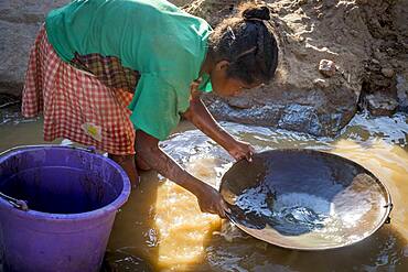 Girl miss school to pan for gold in the mountains near Ankavandra, Madagascar