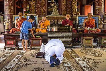 Persons praying, Monks statue, in Wat Phra Singh temple, Chiang Mai, Thailand