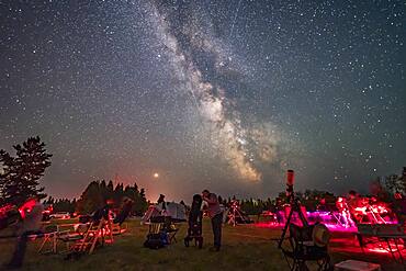 An observer gazes skyward with his Dobsonian reflector telescope at the Saskatchewan Summer Star Party on August 9, 2018, in the Cypress Hills of southwest Saskatchewan, at the Cypress Hills Interprovincial Park, a Dark Sky Preserve. The Milky Way shines to the south. Smoke in the sky obscures the horizon somewhat.