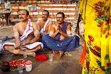 Pilgrims making a ritual offering, and praying, ghats in Ganges river, Varanasi, Uttar Pradesh, India.