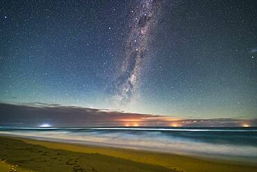 The Dark Emu of aboriginal sky lore rising in a moonlit sky over the Tasman Sea from a beach near Lakes Entrance, Victoria, Australia, April 2, 2017. Lights from fishing boats dot the horizon out at sea. Illumination is from the waxing crescent Moon behind the camera to the north. This is looking southeast. Crux, the Southern Cross, is at top; the Pointer Stars are below.