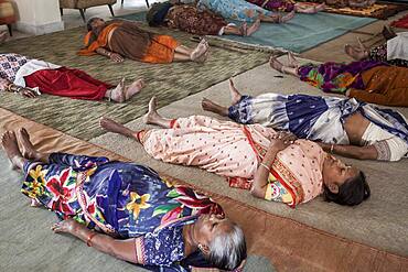 Widows practising Yoga, in Ma Dham ashram for Widows of the NGO Guild for Service, the NGO proposes at widows to wear colorful clothes,  Vrindavan, Mathura district, India