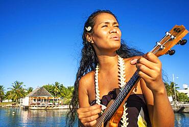 Beautiful local woman playing ukulele in Rangiroa beach, Tuamotu Islands, French Polynesia, South Pacific.