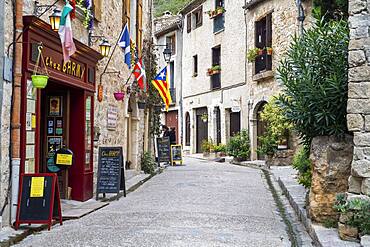 Saint Guilhem le Desert, labelled Les Plus Beaux Villages de France (The Most Beautiful Villages of France), a stop on el Camino de Santiago, Herault, France. Street scene of St Guilhem le Desert, pedestrian road with old historical houses on both side. St-Guilhem, France.