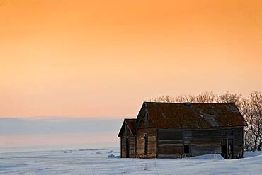 Old barns at prairie sunset in winter.