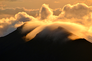 Clouds over a mountain edge at the summit of Haleakala volcano during sunrise, Maui, Hawaii, USA