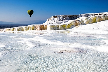 Travertine terrace formations at Pamukkale, tourists and hot-air balloon