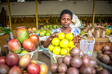 Woman reaches out for fruit in bins at outdoor market, Rwanda Farmers Market, in Rwanda in Rwanda