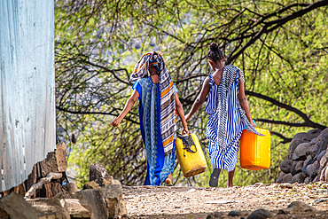 A pair of women carrying containers down a dirt path, Debre Berhan, Ethiopia