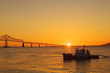 Pilot Boat "Arrow 2" and the Astoria-Megler Bridge, connecting Oregon and Washington across the Columbia River, at sunset; Astoria, Oregon.