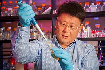 Male scientist in lab using pipette.