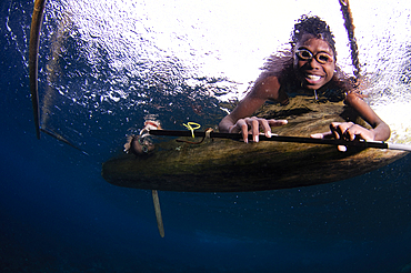 Local children swimming from small outrigger canoes using home made goggles, Alor Island, Nusa Tenggara, Indonesia, Pacific Ocean