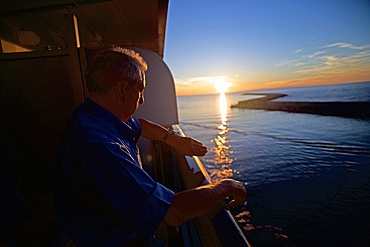 Mature man checking the time in cruise ship at sunset in the Mediterranean