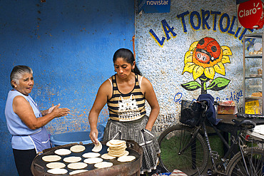 Mayan women baking tortillas in the streets of Antigua, Guatemala, Central America. La Tortolita.