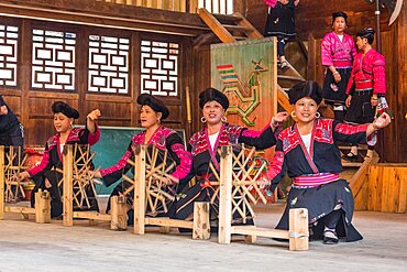 Red Yao ethnic minority women demonstrate spinning thread for weaving their traditional blouses. Huangluo, China.