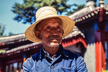 A farmer in his straw hat in an outdoor market in Mutianyu, China.