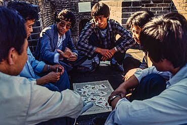 A group of Chinese men playing a card game on the Great Wall of China at Mutianyu, China.