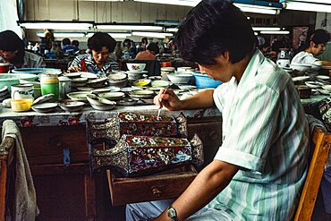 An artisan applies enamel frit with an eyedropper on a cloissone vase in a workshop in Beijing, China.