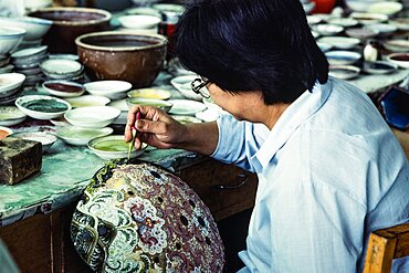 An artisan applies enamel frit with an eyedropper on a cloissone vase in a workshop in Beijing, China.