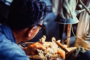 An artisan in a jade factory carves a jade figurine. Beijing, China.