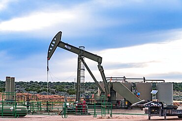 A conventional horsehead oil well pump jack unit and storage tank battery on an oil well site in Utah.