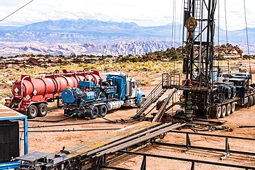 A workover rig with an acid tanker and pumper truck acidizing an oil well to restore production. Utah.