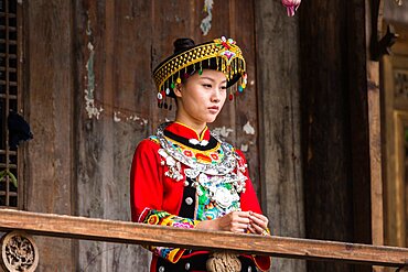 An attractive young woman in traditional ethnic Tujia dress poses for a portrait in Furong, China.