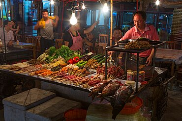 Food vendors with food for sale in the street market at night in the ancient town of Fenghuang, China.