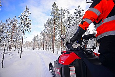 Antti, young Finnish guide from VisitInari, rides a snowmobile in the wilderness of Inari, Lapland, Finland