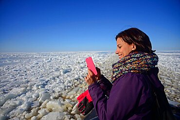 Young woman using mobile phone during Sampo Icebreaker cruise, an authentic Finnish icebreaker turned into touristic attraction in Kemi, Lapland