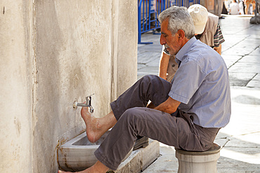 Muslim man washing his feet at the New Mosque, Eminonu Yeni Camii, Eminonu, Istanbul, Turkey