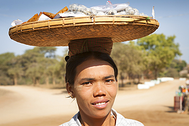 Woman carrying basket of food on her head, Bagan, Myanmar, (Burma)