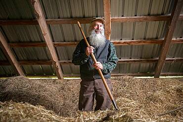 Portrait of a farmer inside a bard filled with hay in Harrison, Maine