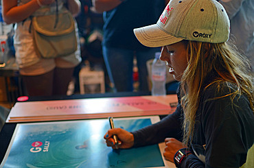 Pro surfer Sally Fitzgibbons signs posters