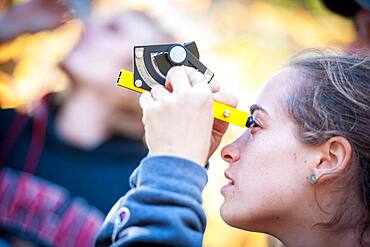 Student using a clinometer to measure the height of a tree.