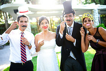 Just married couple playing with costumes and guests in wedding party